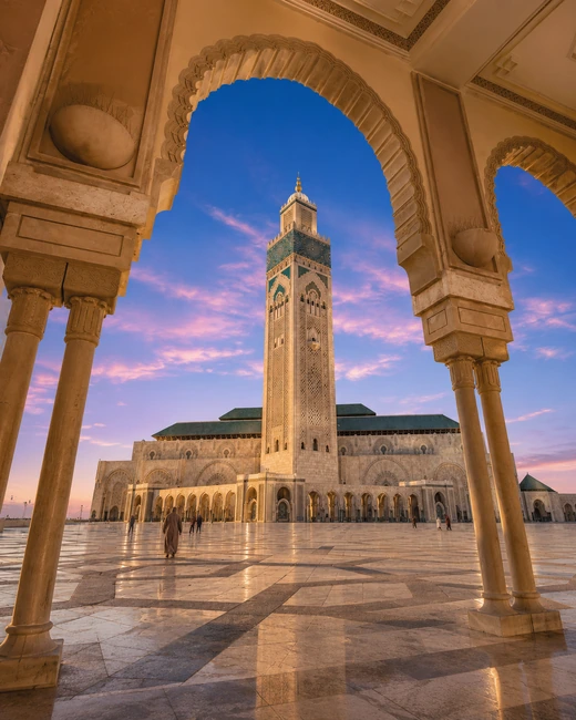 Hassan II Mosque at golden hour framed by a monumental arcade