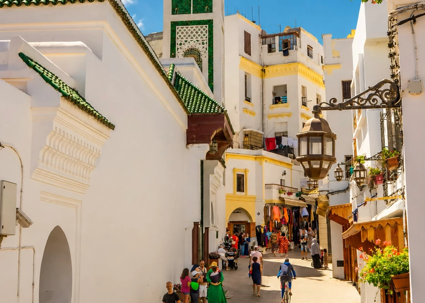 A street with white façades and a green-tiled minaret