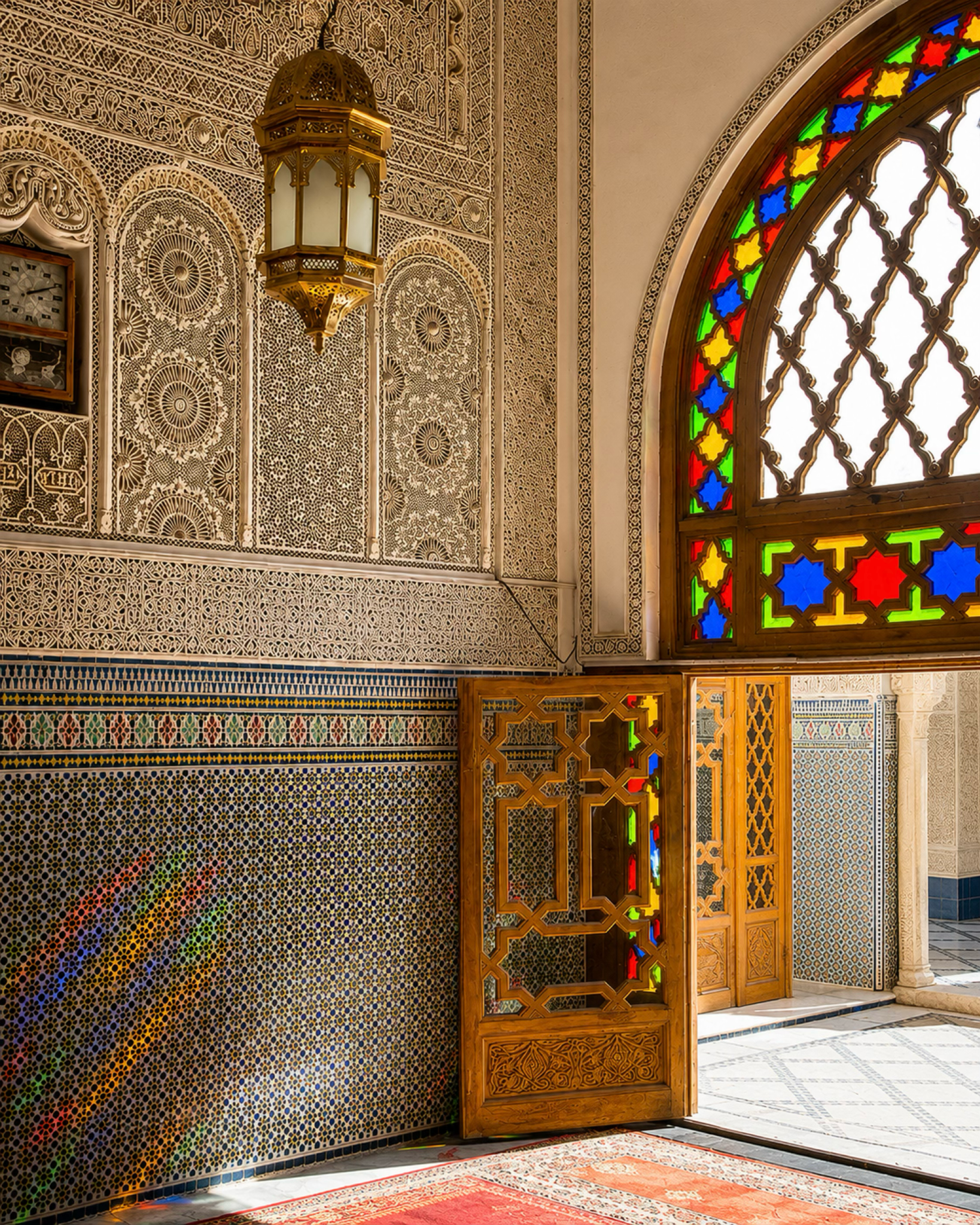 Moroccan interior with zellige, carved plaster, lantern and stained glass