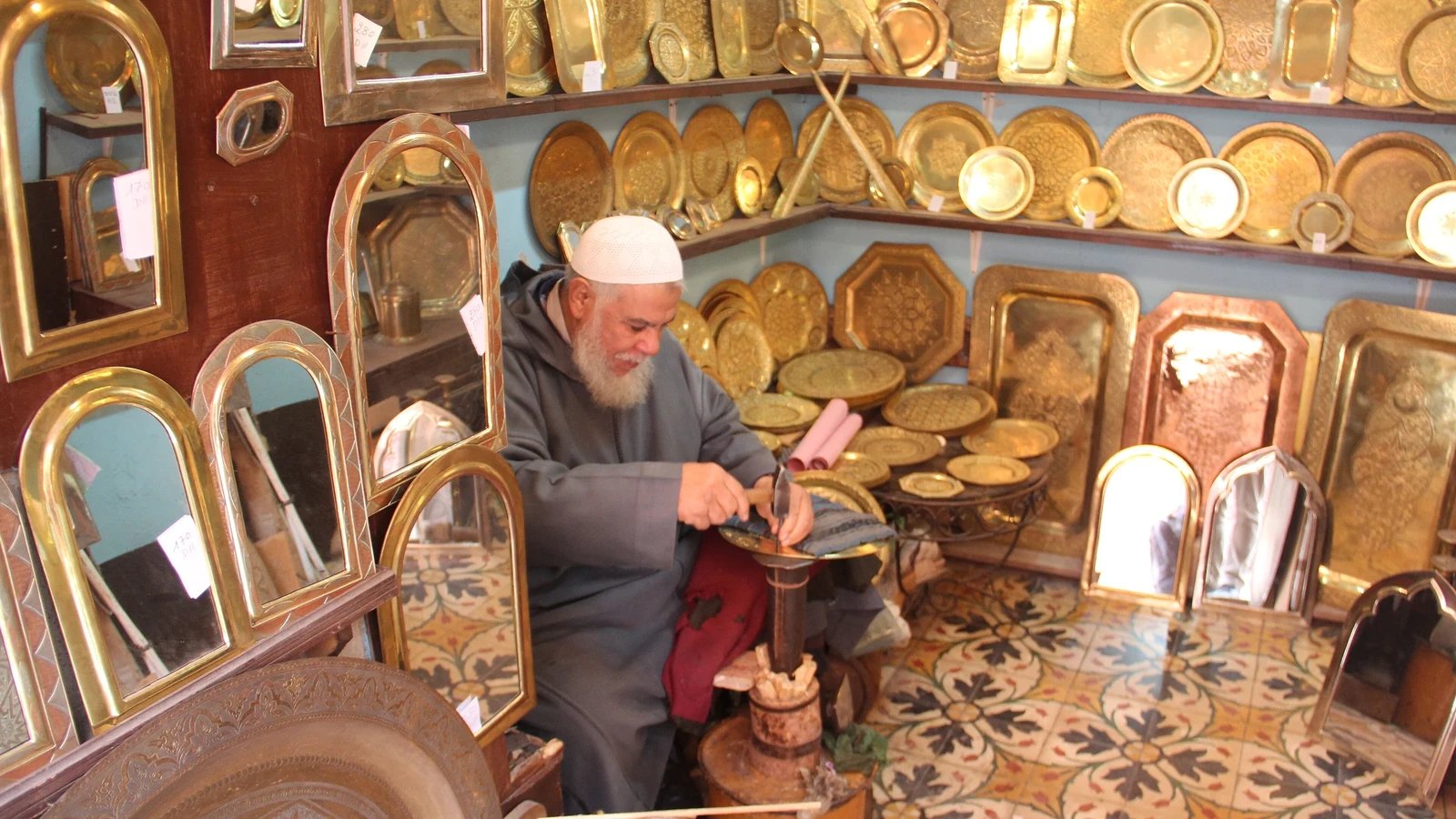 A craftsman working among engraved metal trays and mirrors