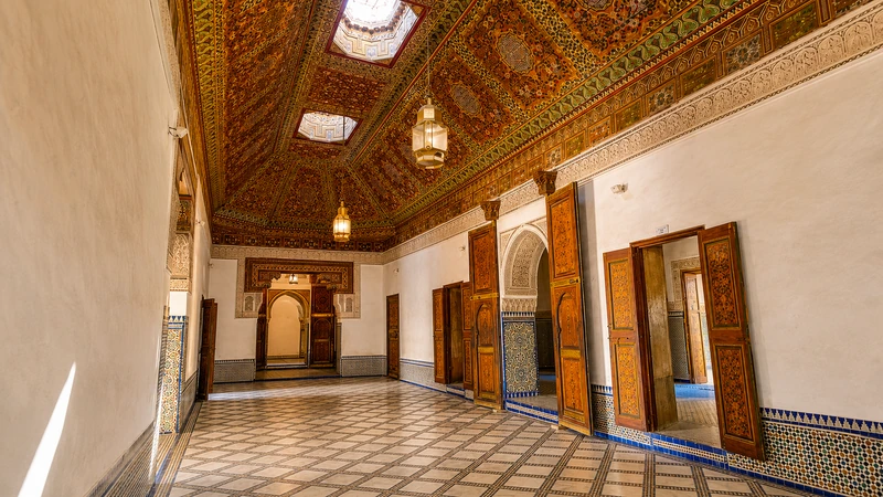 A palace hall with carved and painted timber above zellige walls.