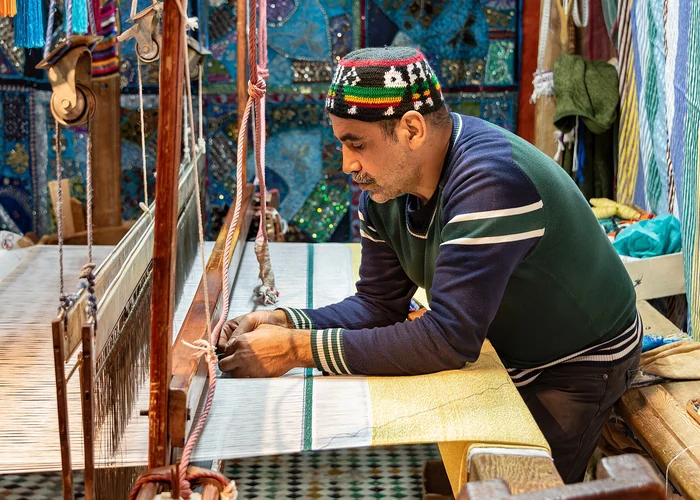 An artisan working at a loom inside a textile workshop