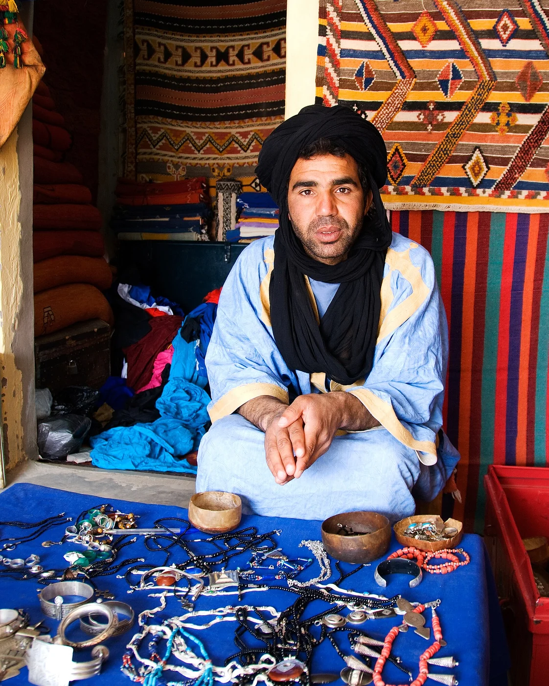 A shopkeeper photographed in M’Hamid. The portrait is independent of the example phrases.