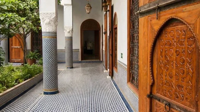 A sheltered domestic gallery, tiled floor and carved door; an existing Exotic Morocco editorial image.
