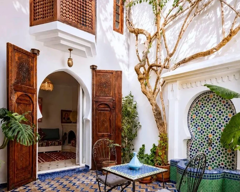 A domestic courtyard with planting, tilework and an open doorway; an existing Exotic Morocco editorial image.