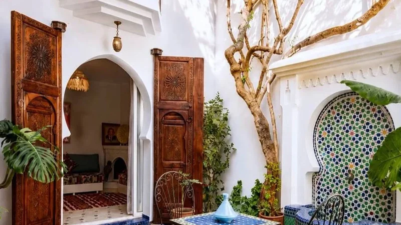 A domestic courtyard with planting, tilework and an open doorway; an existing Exotic Morocco editorial image.