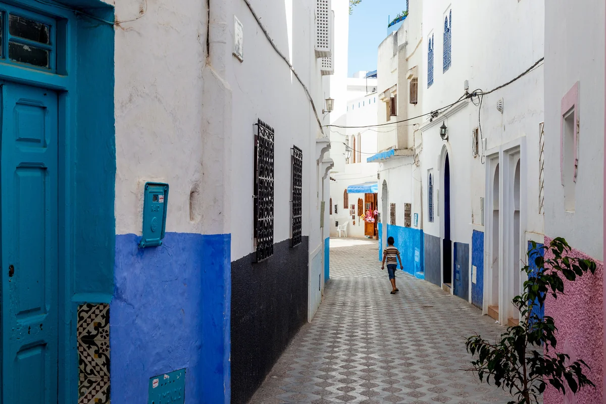 A narrow Asilah lane with blue lower walls and patterned paving