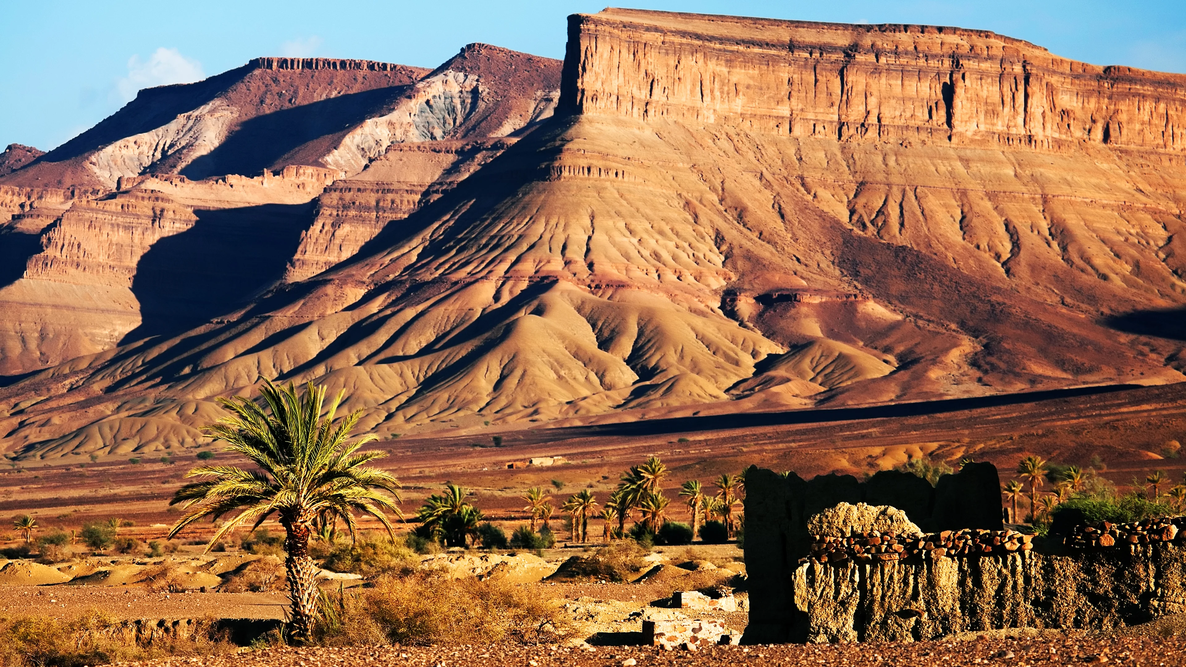 Layered red-rock mountains and a palm-fringed settlement in southern Morocco