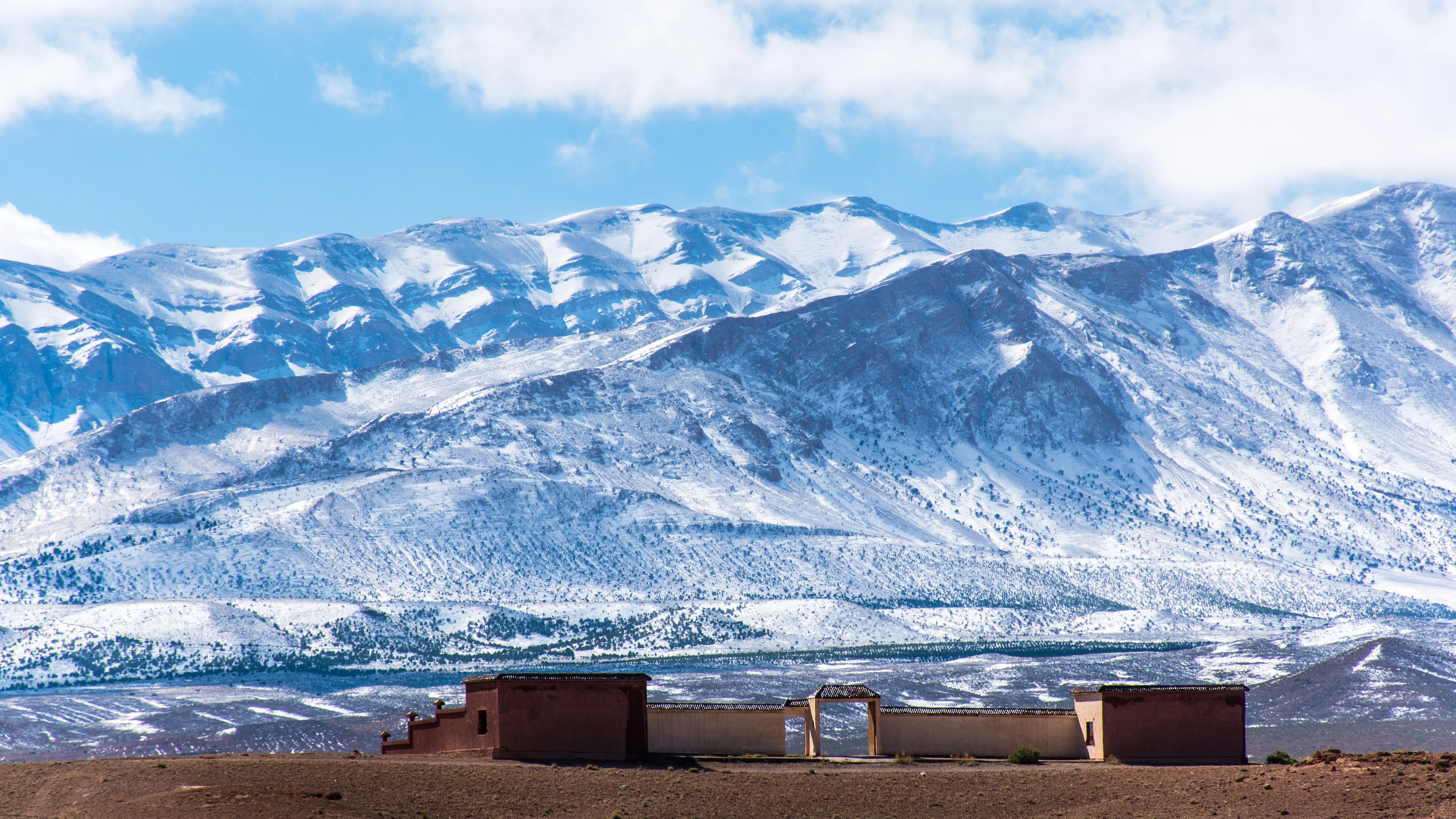 Snow-covered Atlas peaks above an earthen settlement