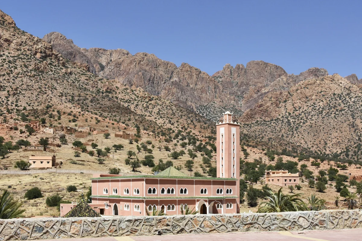 A minaret and village buildings beneath rugged Anti-Atlas mountains