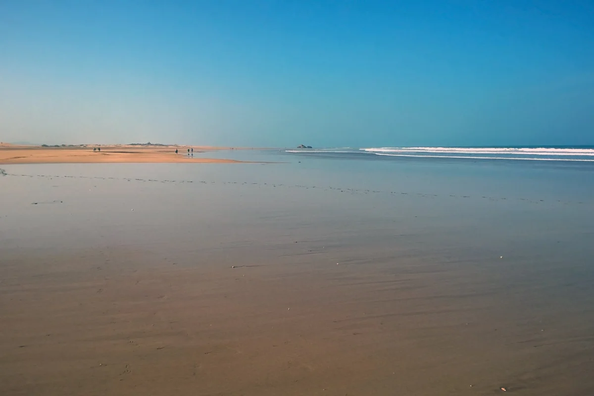Essaouira beach and shallow water beneath a wide blue sky