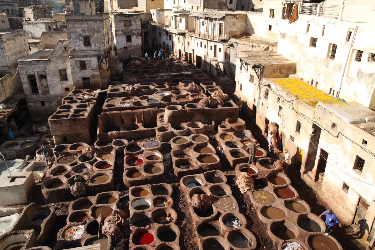 Rows of dyeing vats enclosed by buildings at a Fès tannery
