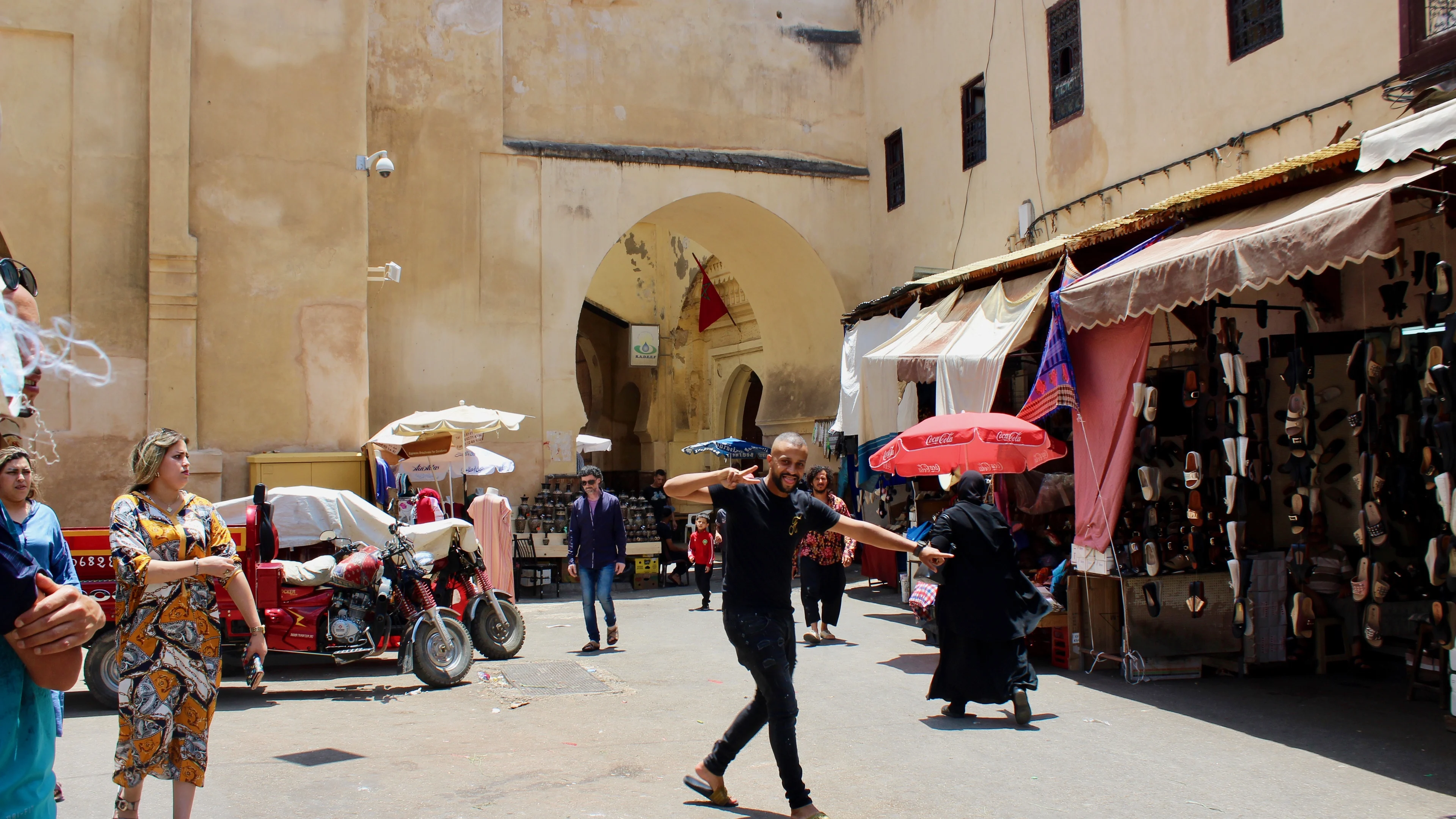 People and market stalls at a gateway in the Fès medina