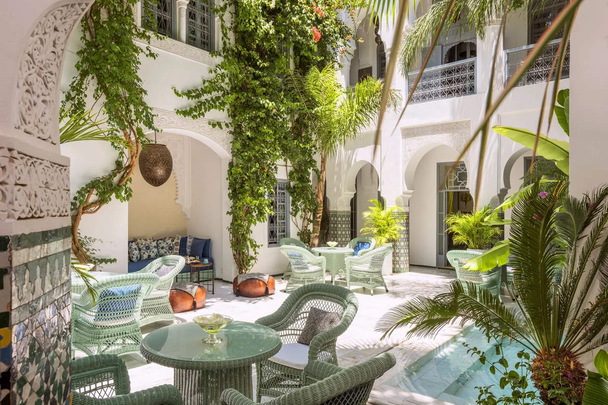 Wicker seating and plants in a bright Moroccan riad courtyard