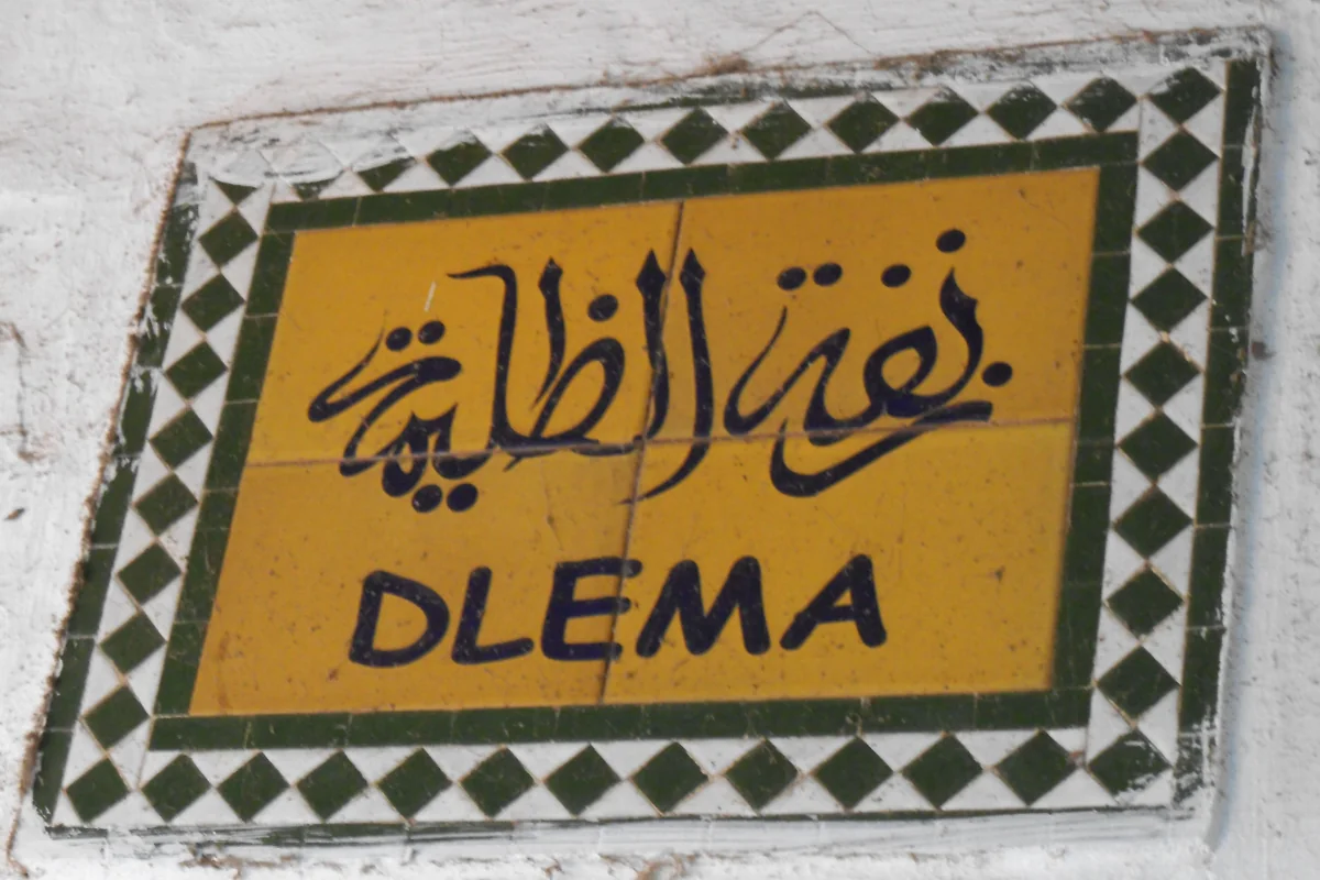 A yellow and blue street sign on a wall in Tetouan