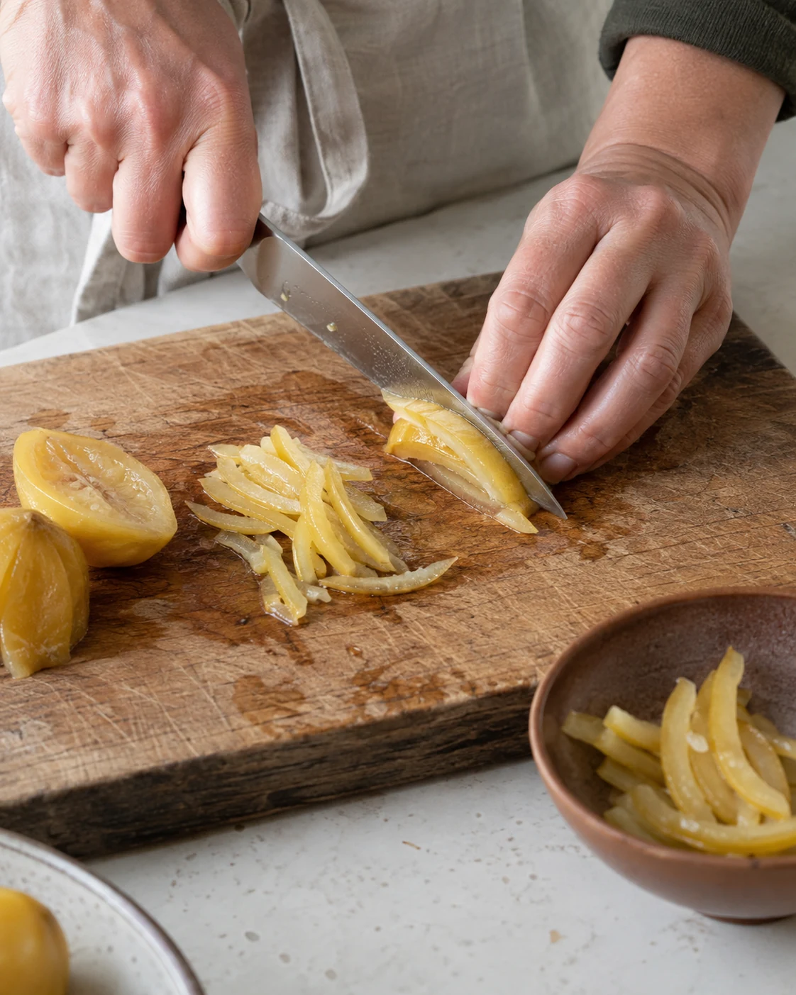 Hands slicing salt-preserved lemon peel