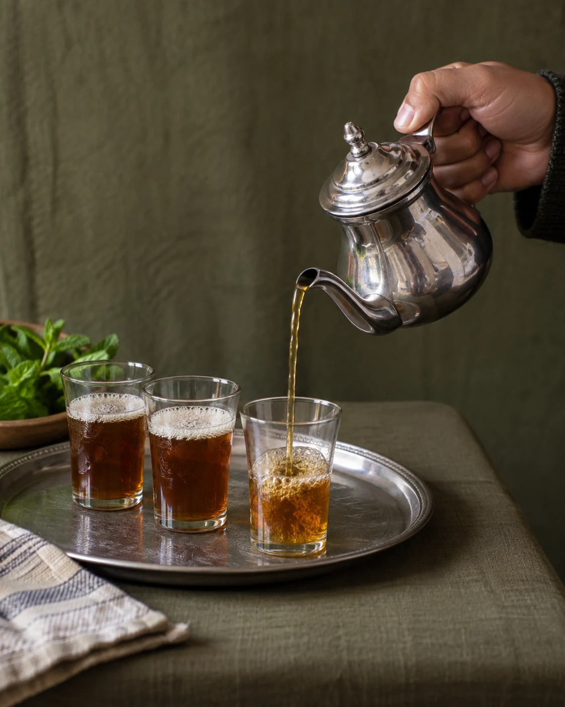 Three small glasses being filled for a round of tea