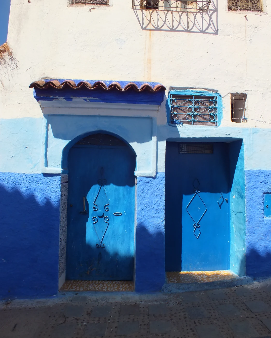 Blue doors and white walls on a residential street in Chefchaouen.