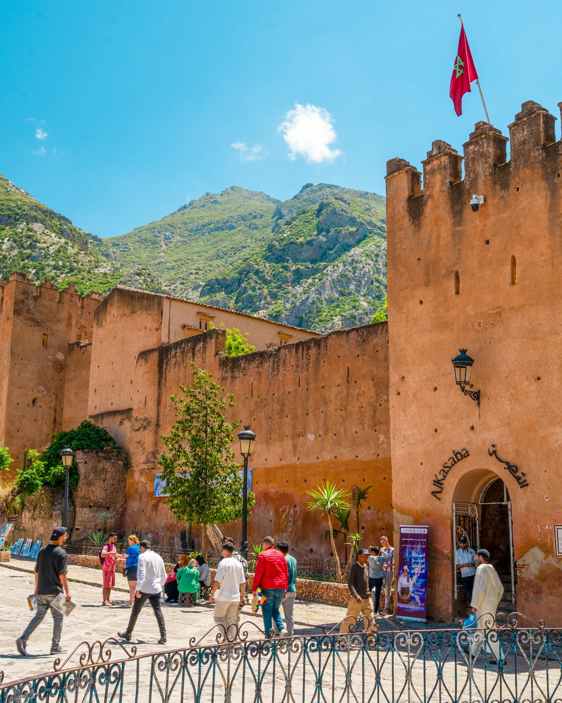 Ochre kasbah towers and public space in Chefchaouen with the Rif behind them.