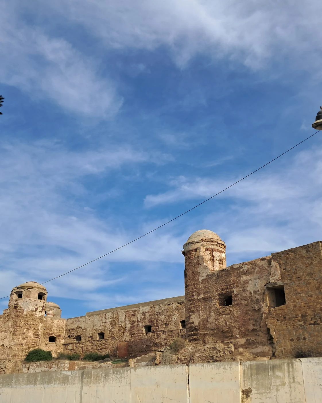 Historic fortified walls and a small round tower in Larache.