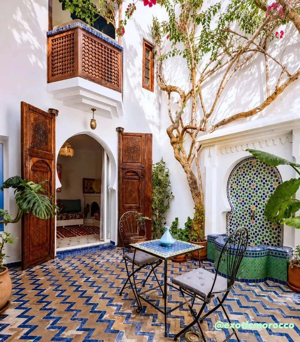 Planting, carved doors and tiled surfaces around a bright courtyard