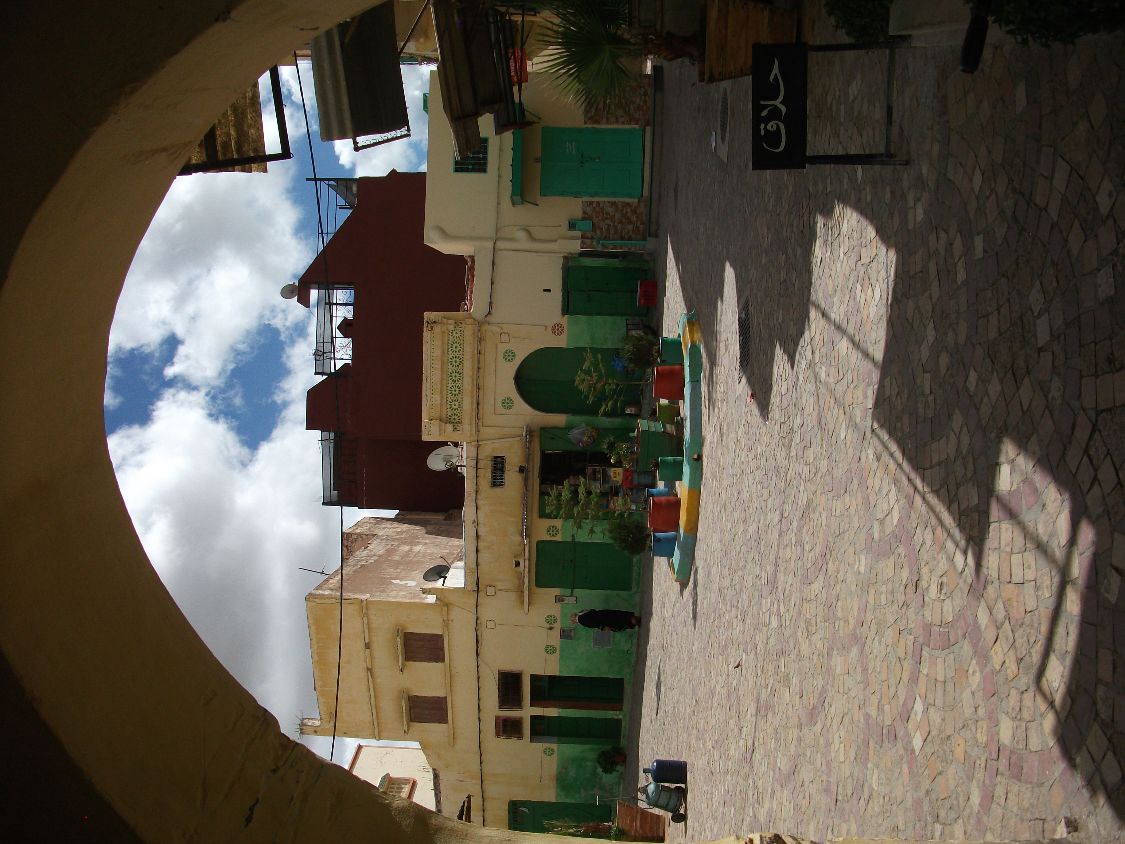 Arch opening onto a courtyard with green doors and plants in Boujaad medina