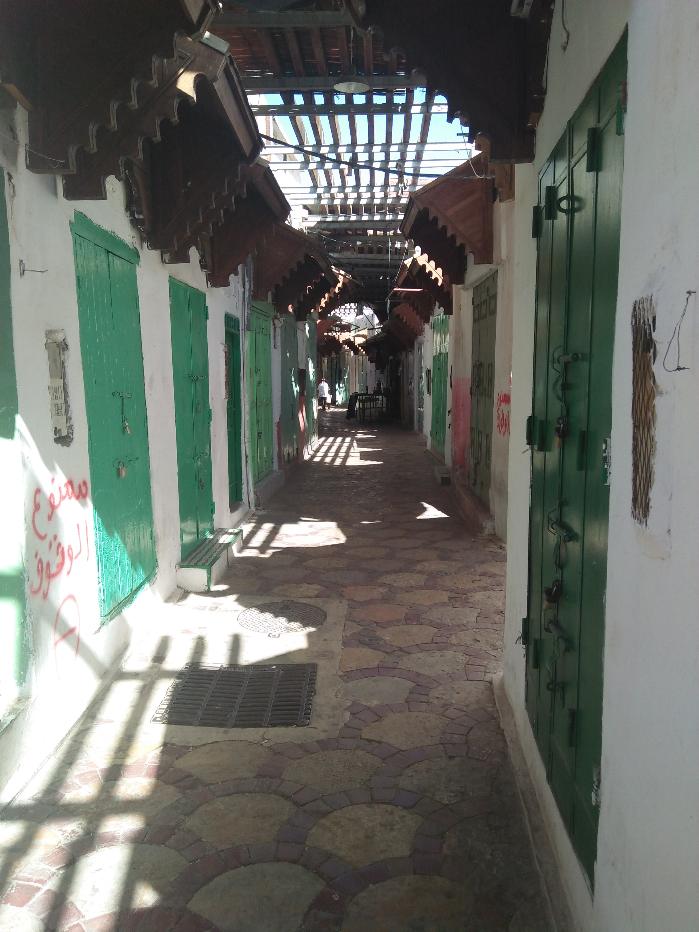 Covered market passage with green shop doors in Bejaad medina