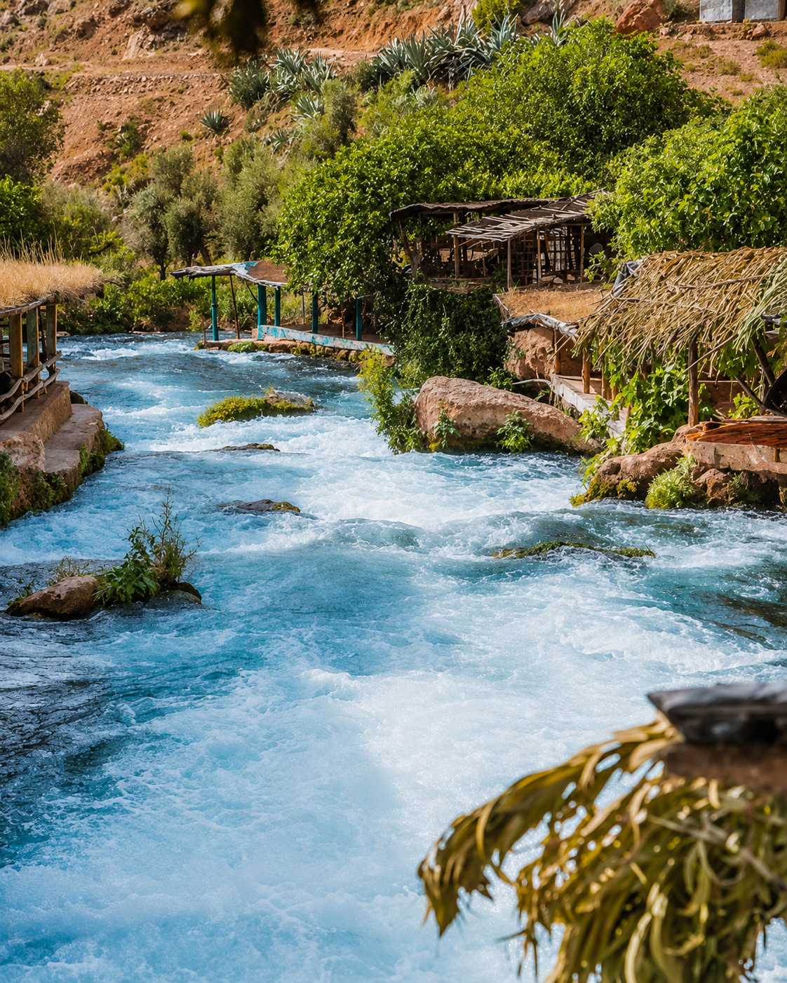 Fast-flowing turquoise water between rocky banks and mountain vegetation