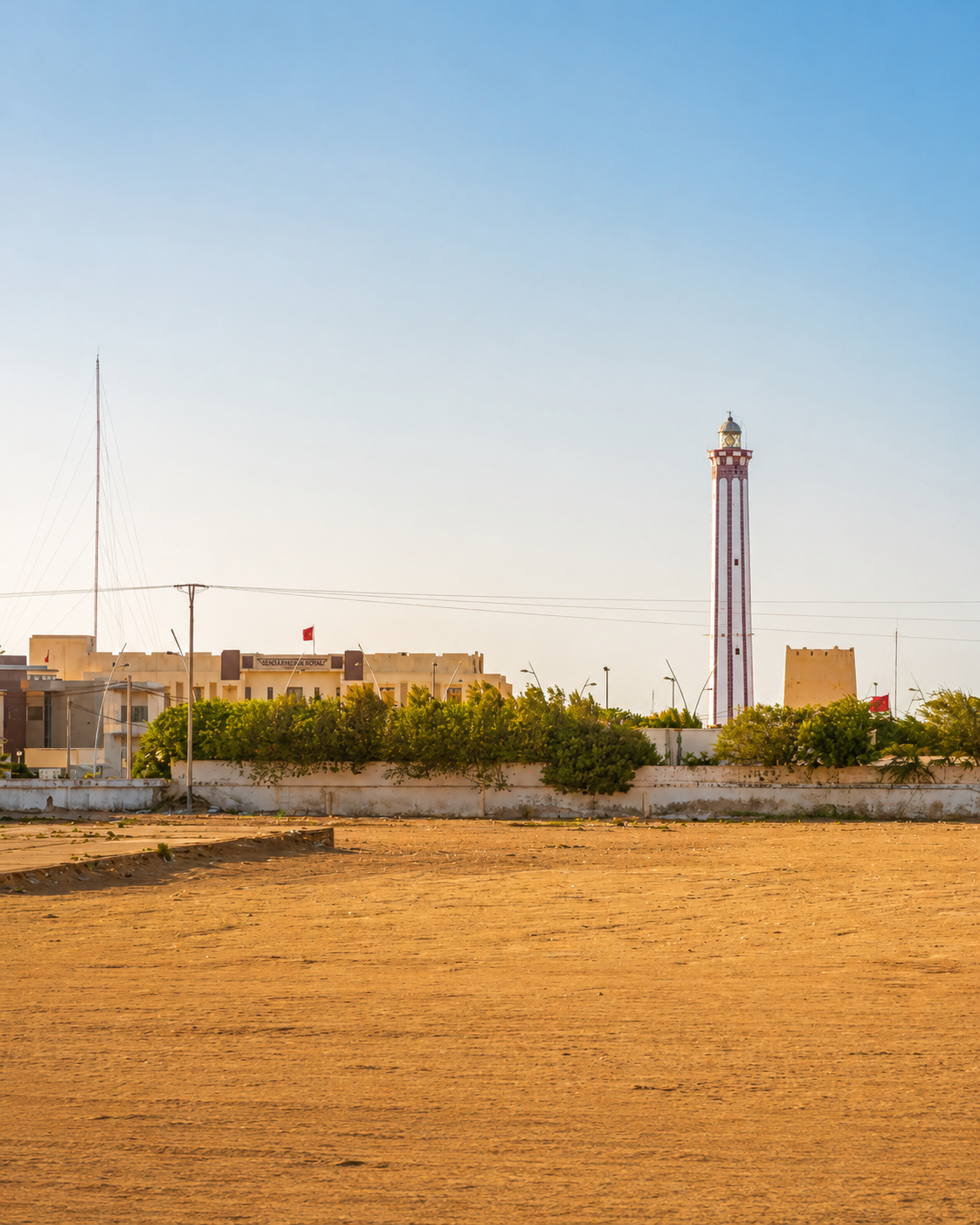 Boujdour lighthouse rising above low buildings and an open sandy foreground