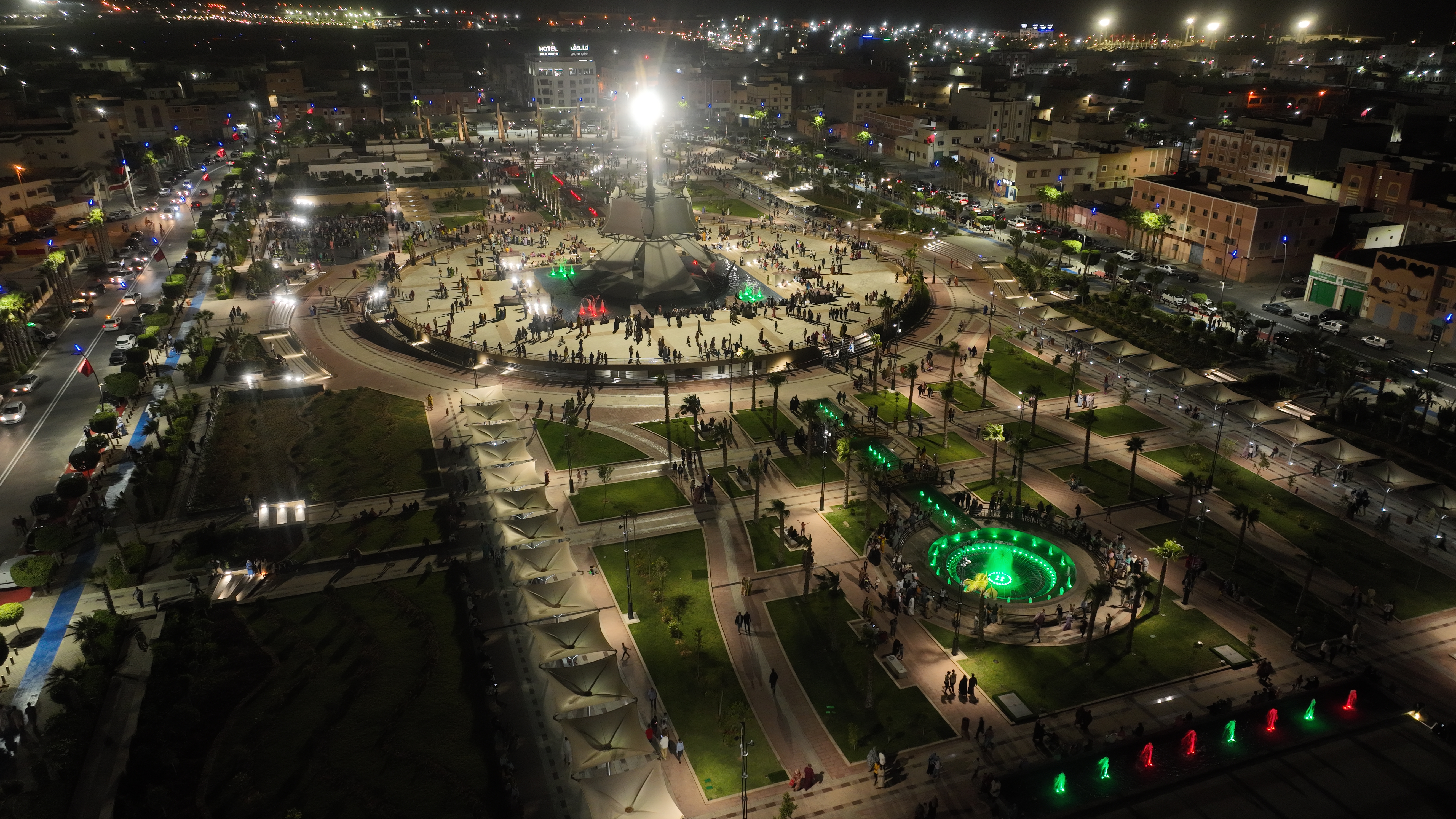 Aerial photograph of Laâyoune's illuminated central square, fountains and surrounding city streets at night
