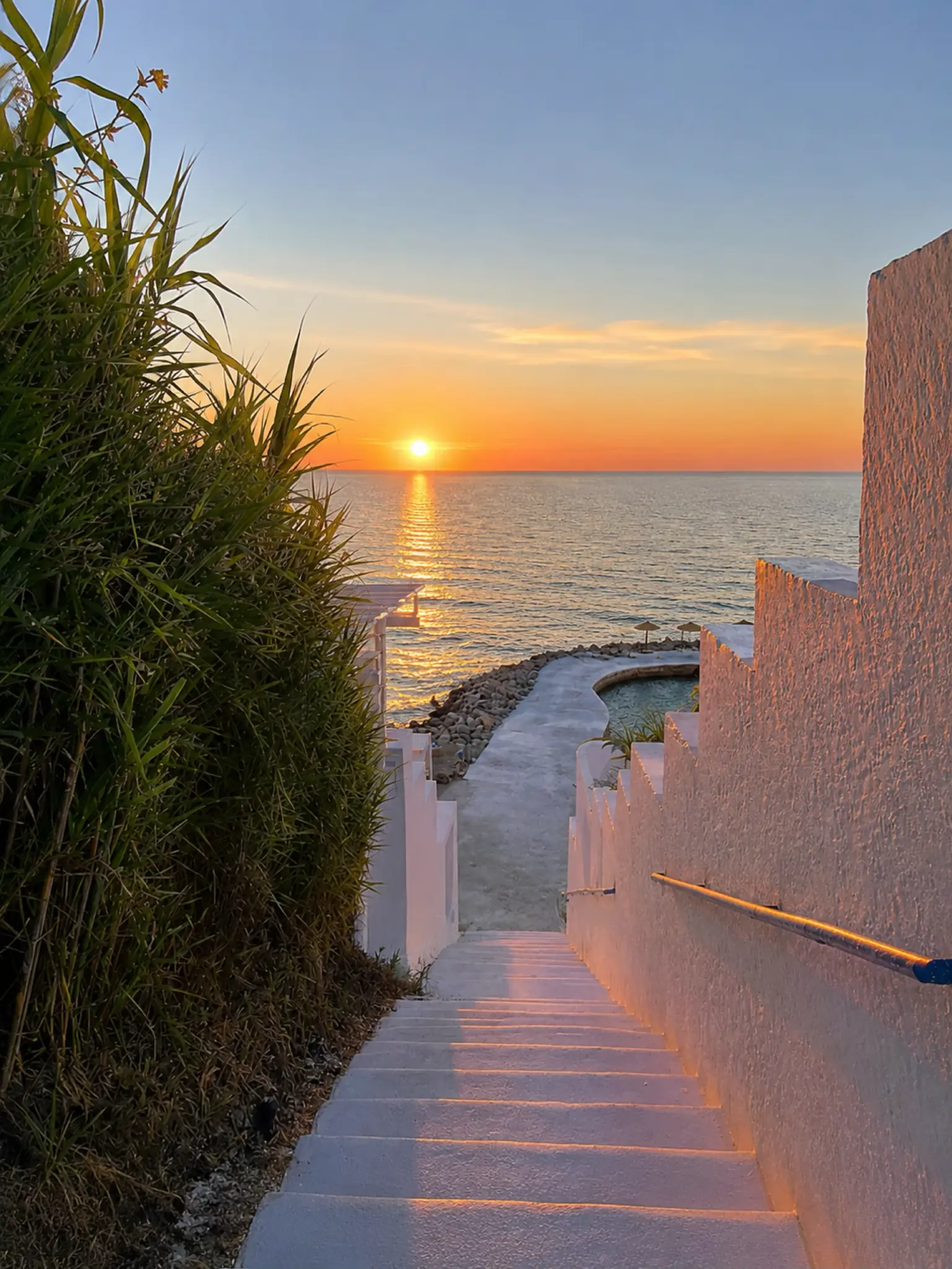 A white stairway descending toward the Mediterranean at sunset in Cabo Negro