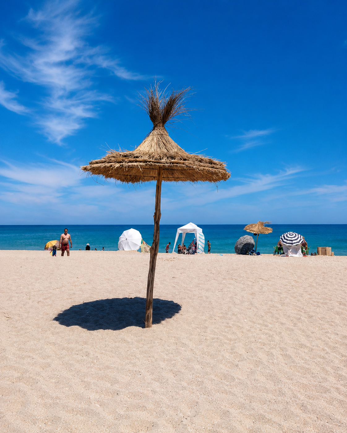 Straw beach parasol casting a shadow beside the Mediterranean