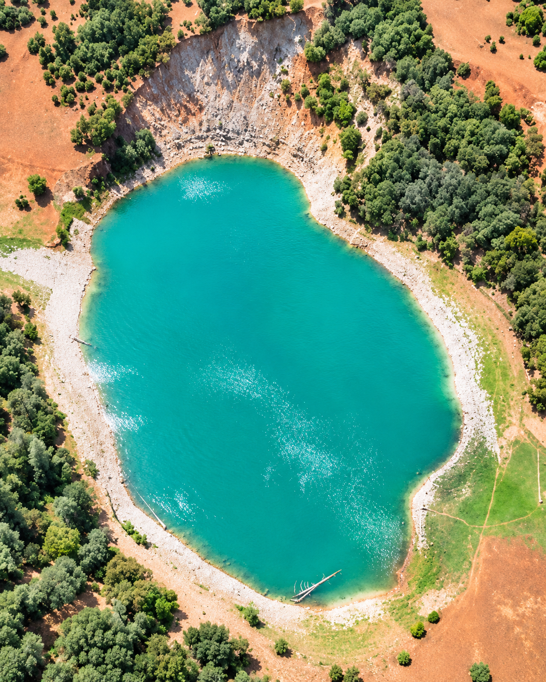 Overhead view of a turquoise mountain lake and its wooded shore in the Khenifra image collection