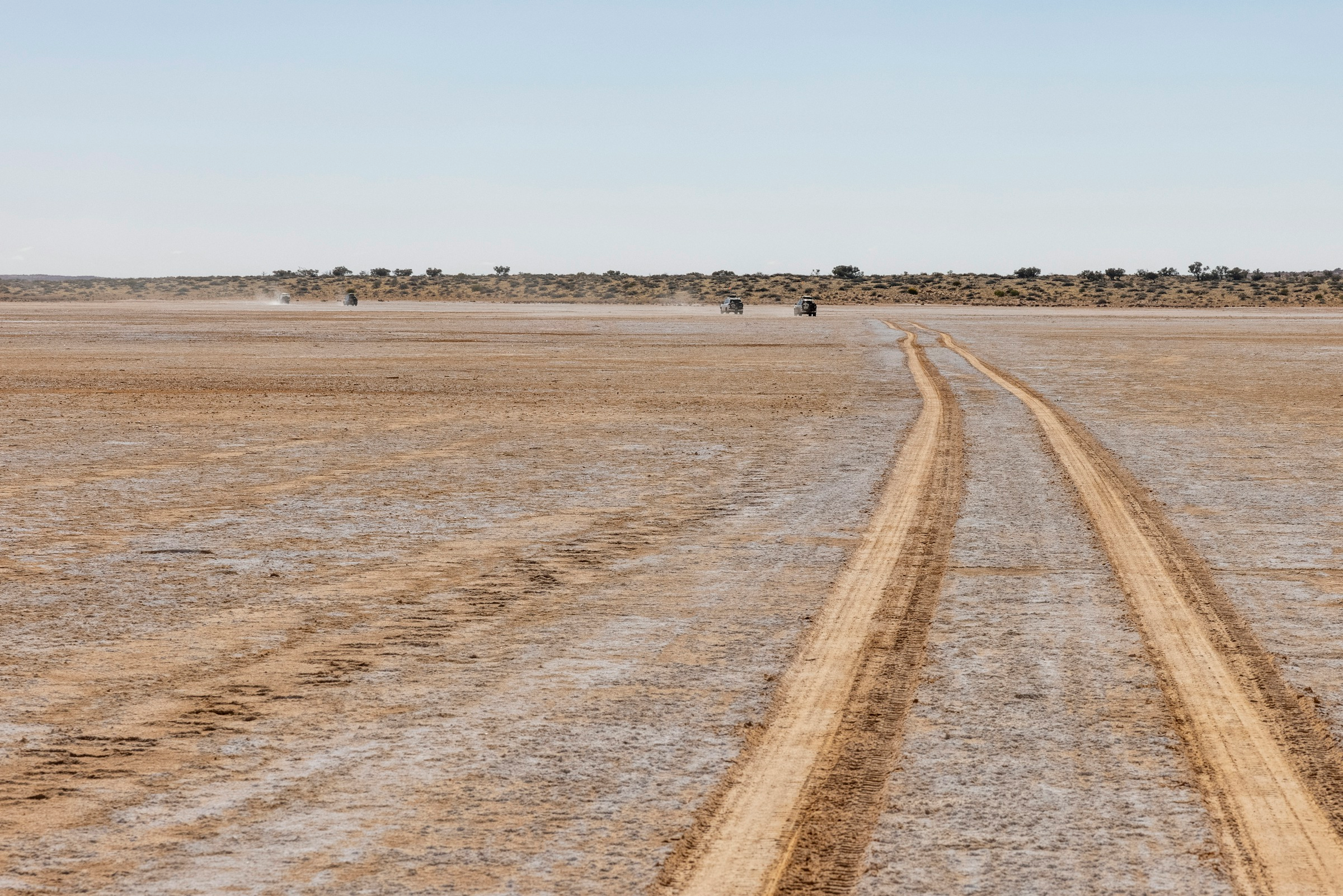 Vehicles crossing the broad, flat dry lakebed in Iriqui National Park