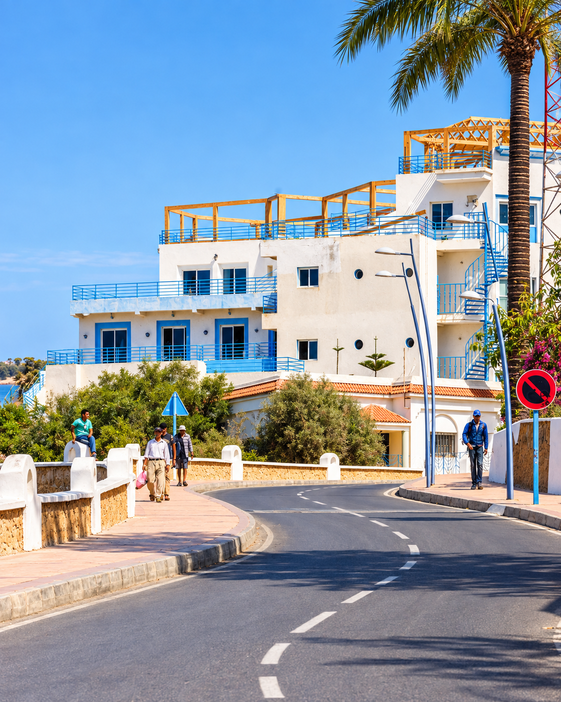 White seaside building with blue shutters beside a curving street in Oualidia