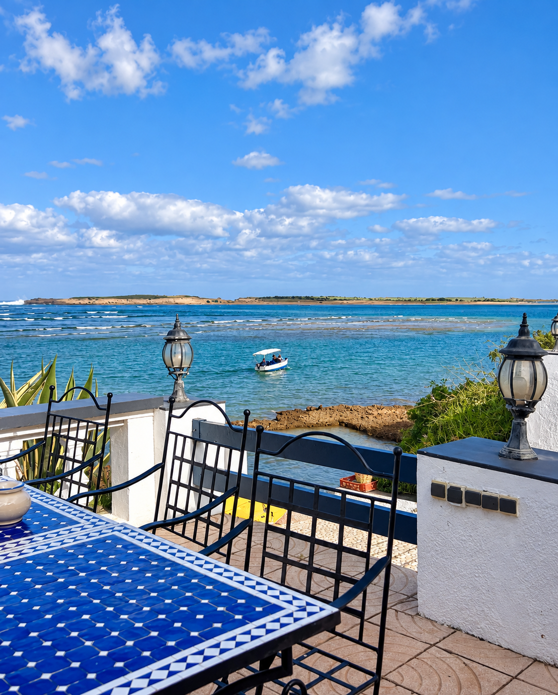 A boat crossing Oualidia lagoon seen from a terrace with blue zellige and lanterns