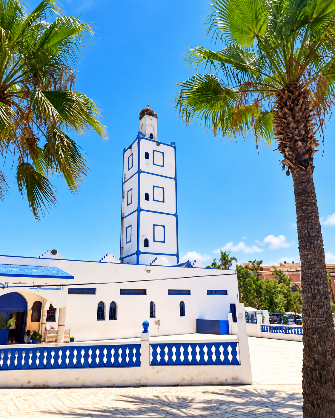 White and blue minaret framed by palms in Oualidia