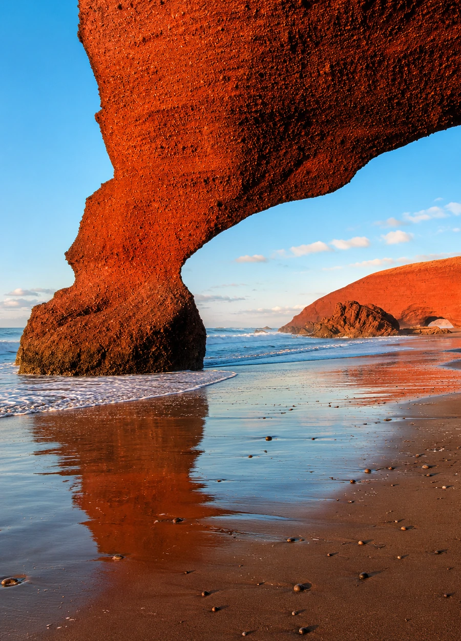 Legzira sandstone arch reflected on the shoreline near Sidi Ifni