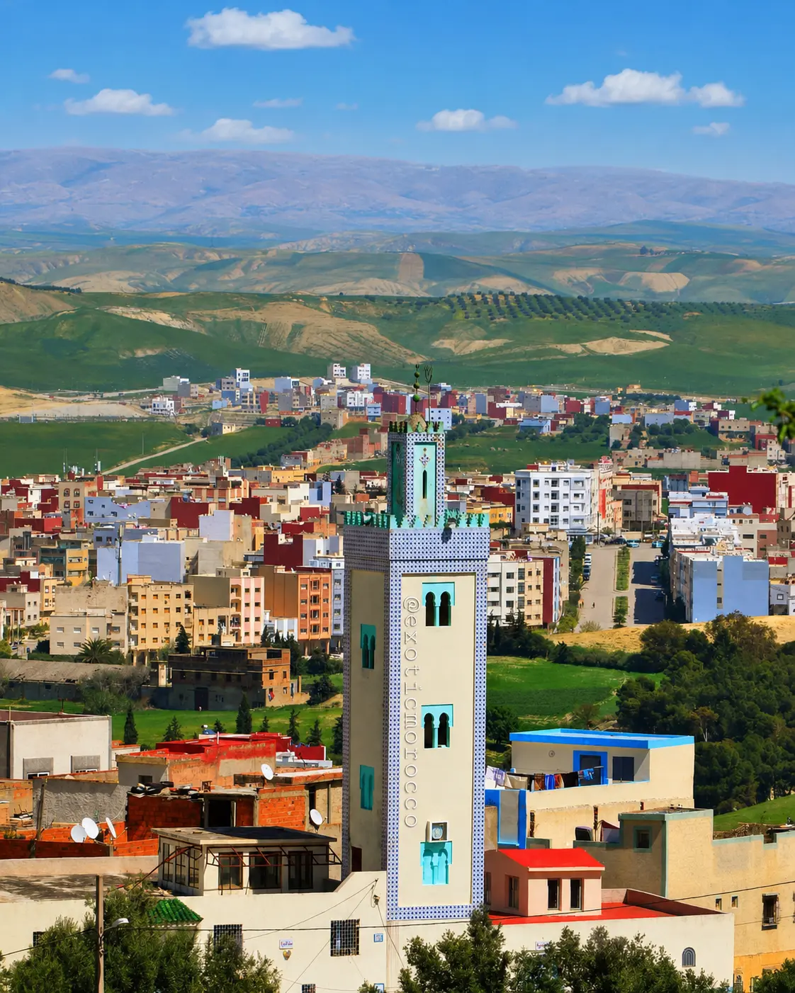 Taza city with a minaret, colourful buildings and mountain landscape in the background