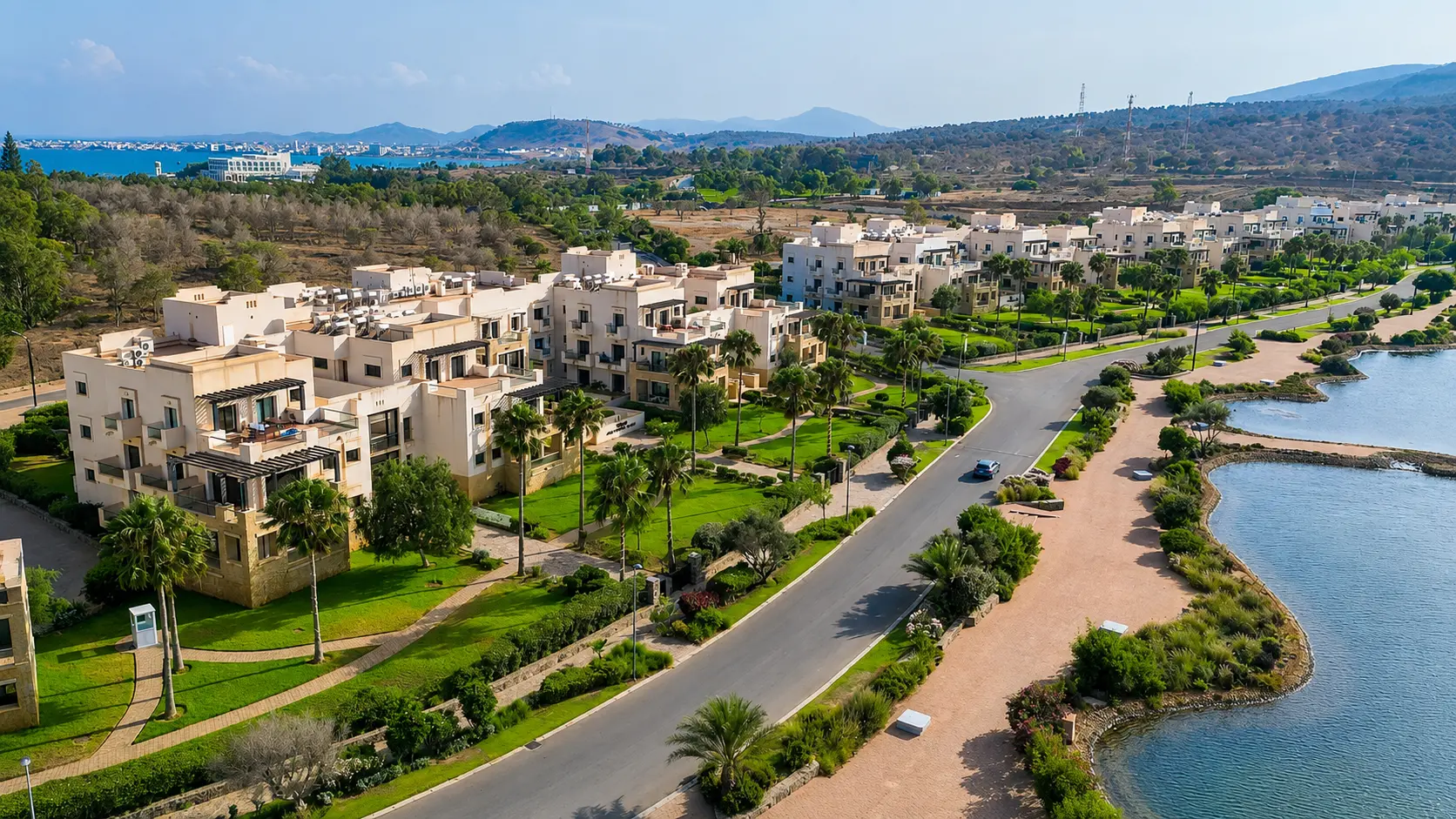 Marchica Lagoon waterfront near Nador with palms, gardens, blue water and mountain horizons