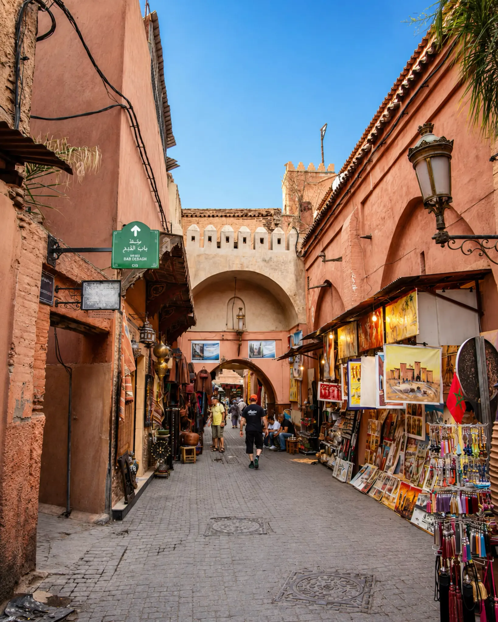 Marrakech medina passage with rose-toned walls and craft stalls, the city context for Menara Gardens