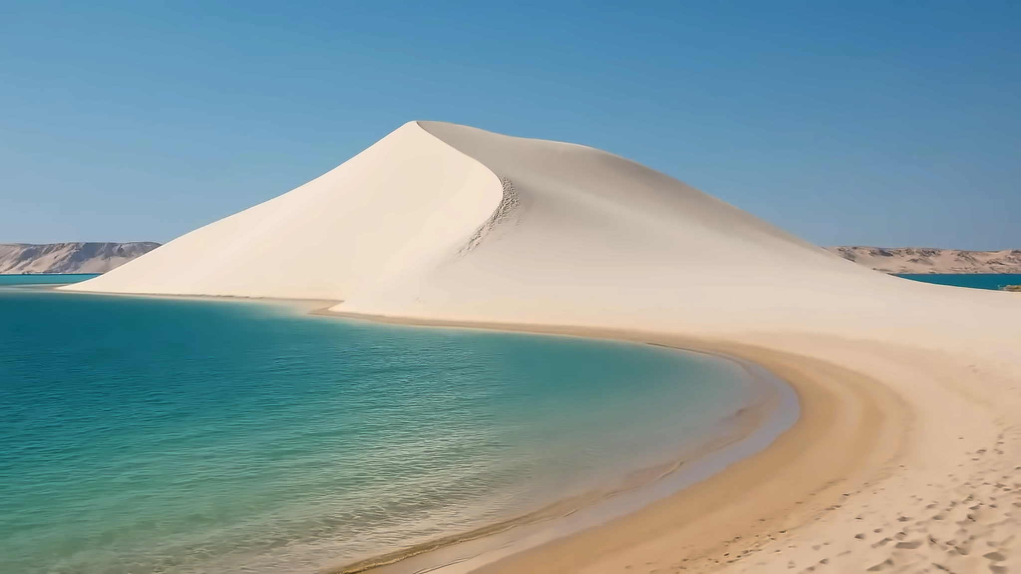White Dune rising beside turquoise lagoon water near Dakhla, Morocco